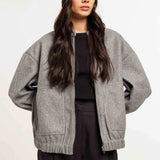 Woman wearing a gray cardigan, black top, and pants with a black beanie on a white background