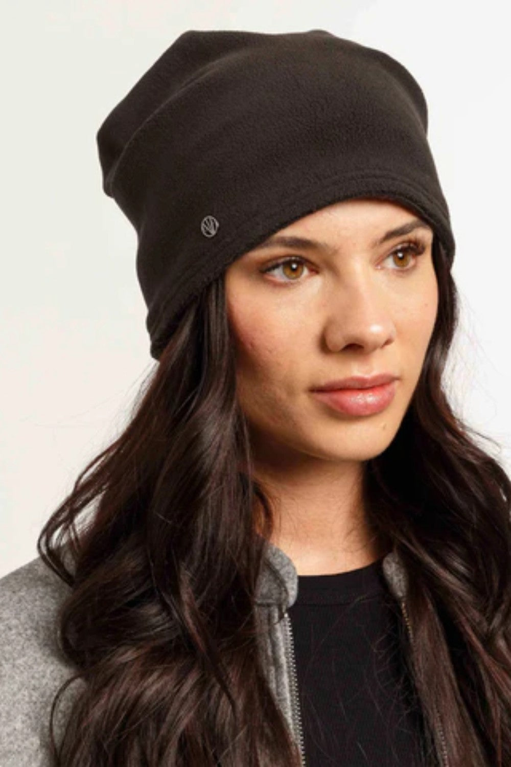 Woman wearing a black beanie against a plain background