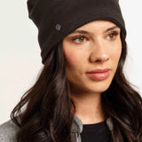Woman wearing a black beanie against a plain background