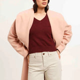 Woman wearing a pink cardigan, burgundy hat, and beige pants on a white background