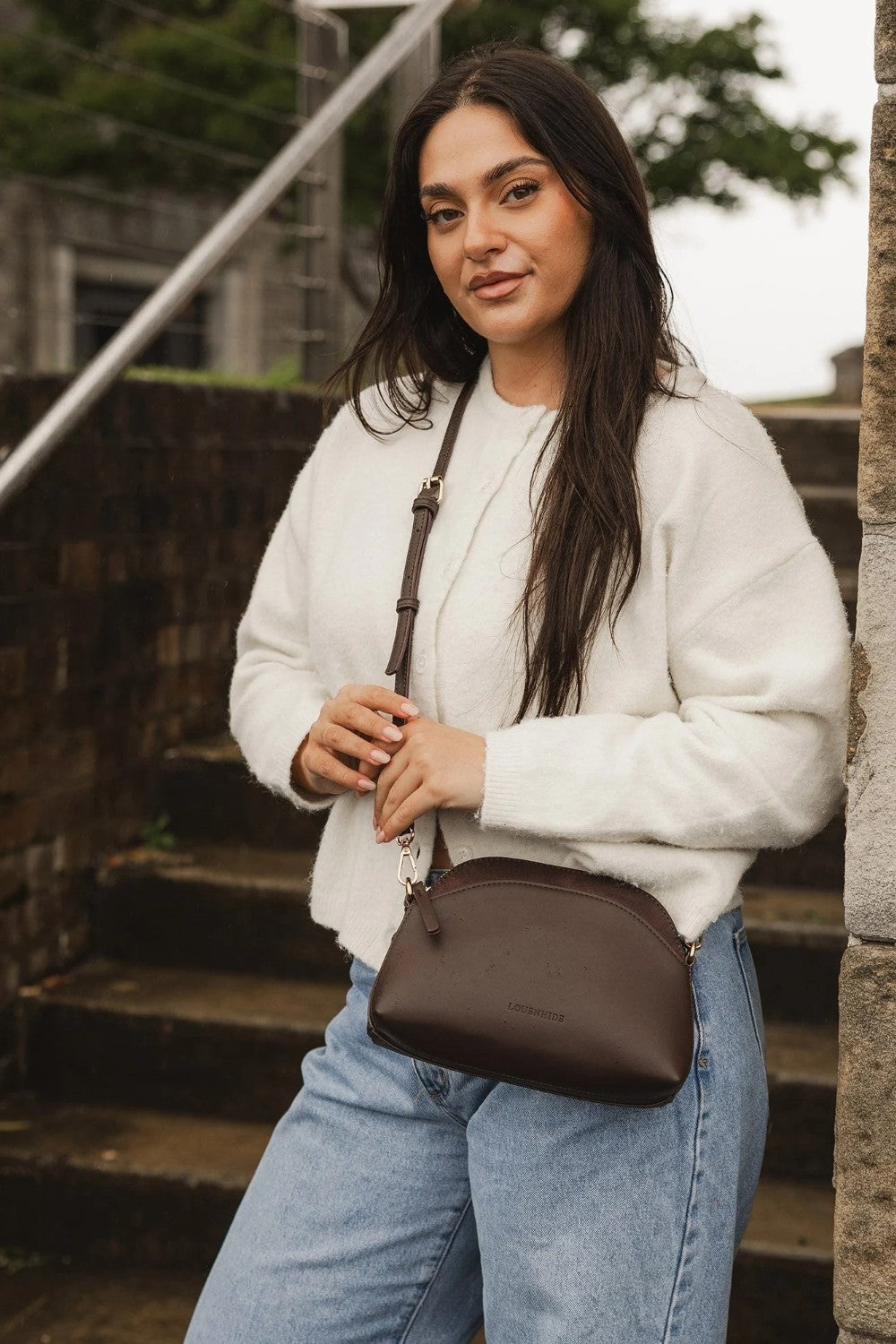 Woman holding a brown pleather bag outdoors on stone steps