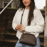 Woman holding a brown pleather bag outdoors on stone steps