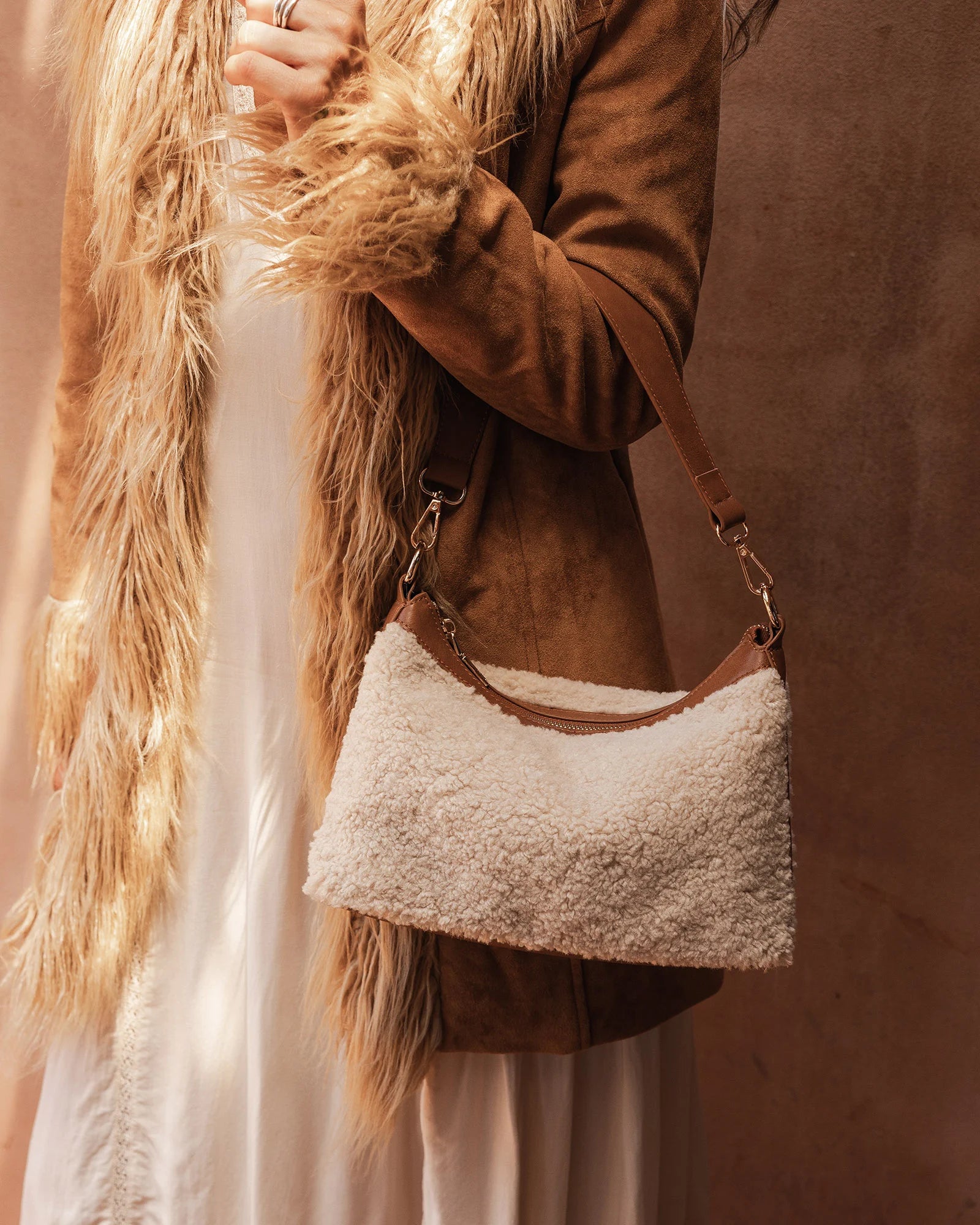 The Louenhide Aspen Shoulder Bag is the soft-structured silhouette your winter wardrobe’s been waiting for. Crafted in a faux shearling texture with warm neutral tones, this sherpa bag brings a subtle warmth to cool-weather dressing. Light gold hardware adds a refined touch to this beige shoulder bag, while the spacious interior easily fits your daily essentials. Whether styled with denim or layered with flowing silhouettes, the Aspen is designed to move with you through the season - statement, elevated, an