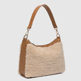 The Louenhide Aspen Shoulder Bag is the soft-structured silhouette your winter wardrobe’s been waiting for. Crafted in a faux shearling texture with warm neutral tones, this sherpa bag brings a subtle warmth to cool-weather dressing. Light gold hardware adds a refined touch to this beige shoulder bag, while the spacious interior easily fits your daily essentials. Whether styled with denim or layered with flowing silhouettes, the Aspen is designed to move with you through the season - statement, elevated, an