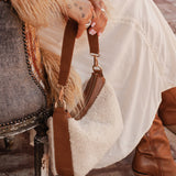 The Louenhide Aspen Shoulder Bag is the soft-structured silhouette your winter wardrobe’s been waiting for. Crafted in a faux shearling texture with warm neutral tones, this sherpa bag brings a subtle warmth to cool-weather dressing. Light gold hardware adds a refined touch to this beige shoulder bag, while the spacious interior easily fits your daily essentials. Whether styled with denim or layered with flowing silhouettes, the Aspen is designed to move with you through the season - statement, elevated, an