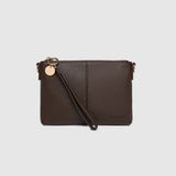 A dark brown pebbled leather clutch bag with a wristlet strap and a small gold-tone charm, shown against a light gray background.