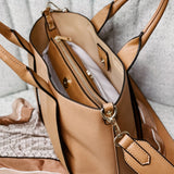 Tan leather handbag with gold accents on a light gray surface