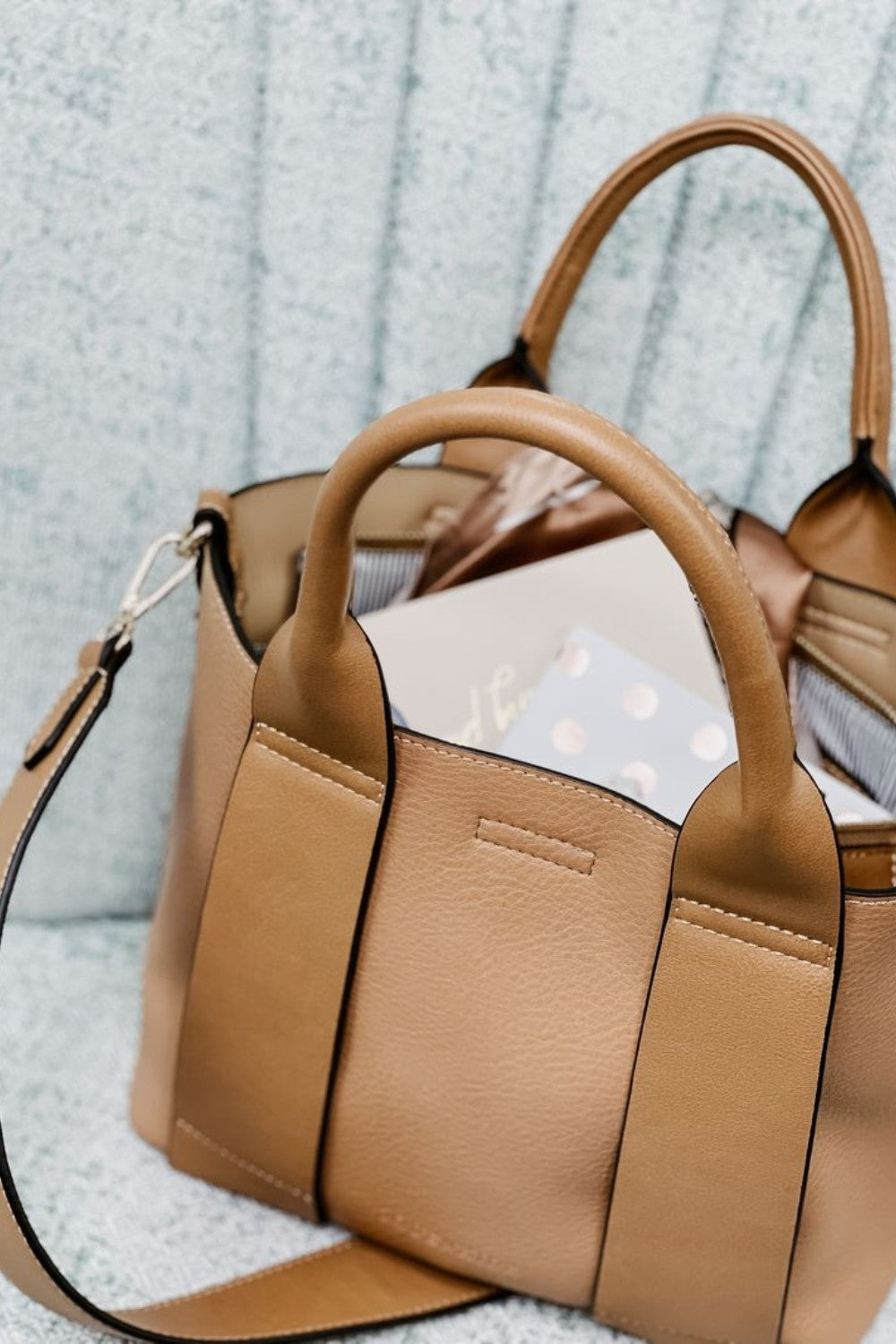 Tan handbag with a strap on a textured surface