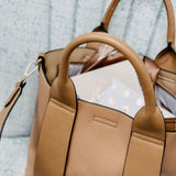 Tan handbag with a strap on a textured surface