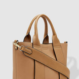 Tan handbag with a shoulder strap on a light gray background