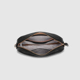 A black zippered bag shown open from a top-down view, revealing a striped interior lining and gold-toned zipper hardware, set against a solid light gray background.