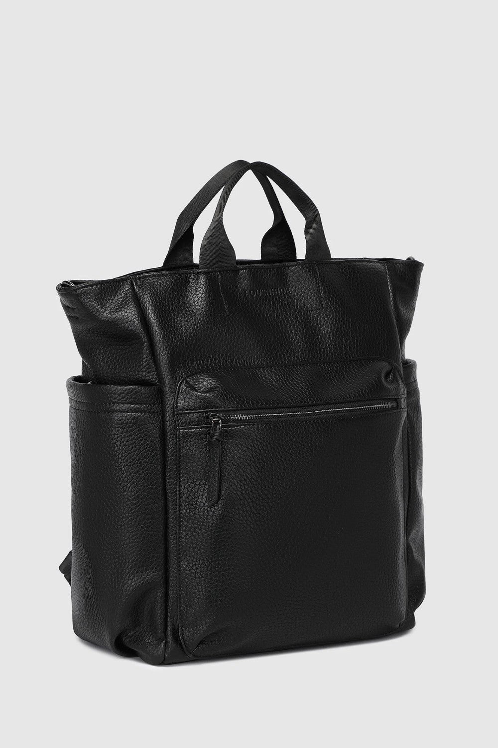 A black pebbled faux-leather backpack with top handles and a front zippered pocket, shown from a three-quarter angle against a light gray background.