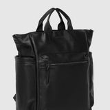 A black pebbled faux-leather backpack with top handles and a front zippered pocket, shown from a three-quarter angle against a light gray background.
