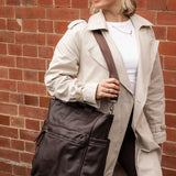 Woman holding a brown pleather bag against a brick wall