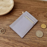 Lilac wallet with card slots and coins on a wooden surface
