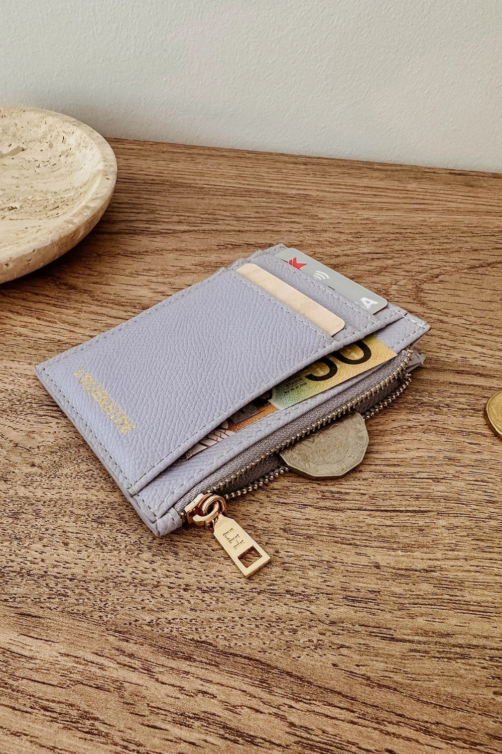 Lilac wallet with gold accents on a wooden surface