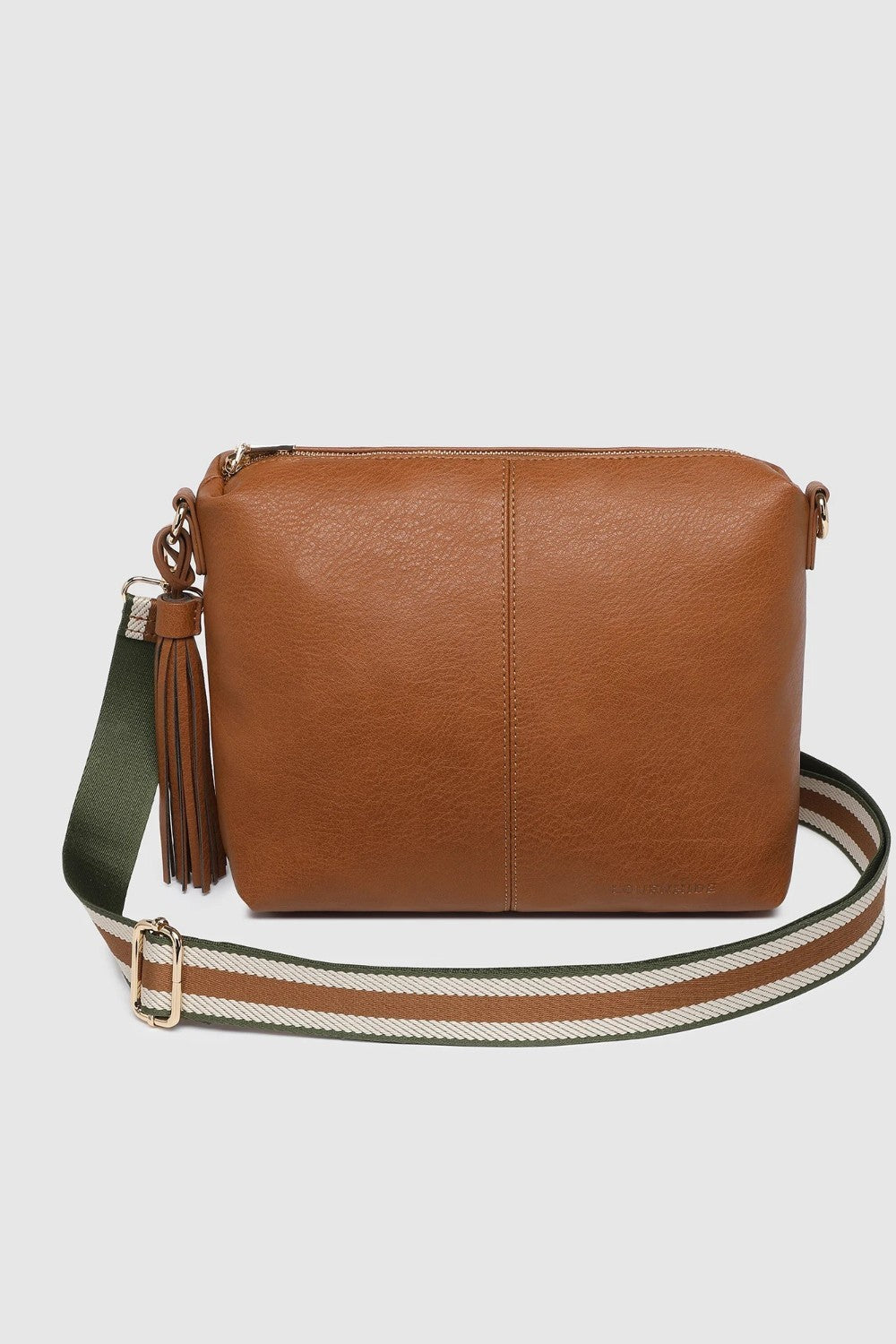 A tan leather crossbody bag with a green and white striped woven strap, featuring a brown leather tassel charm on the side, set against a light gray background.