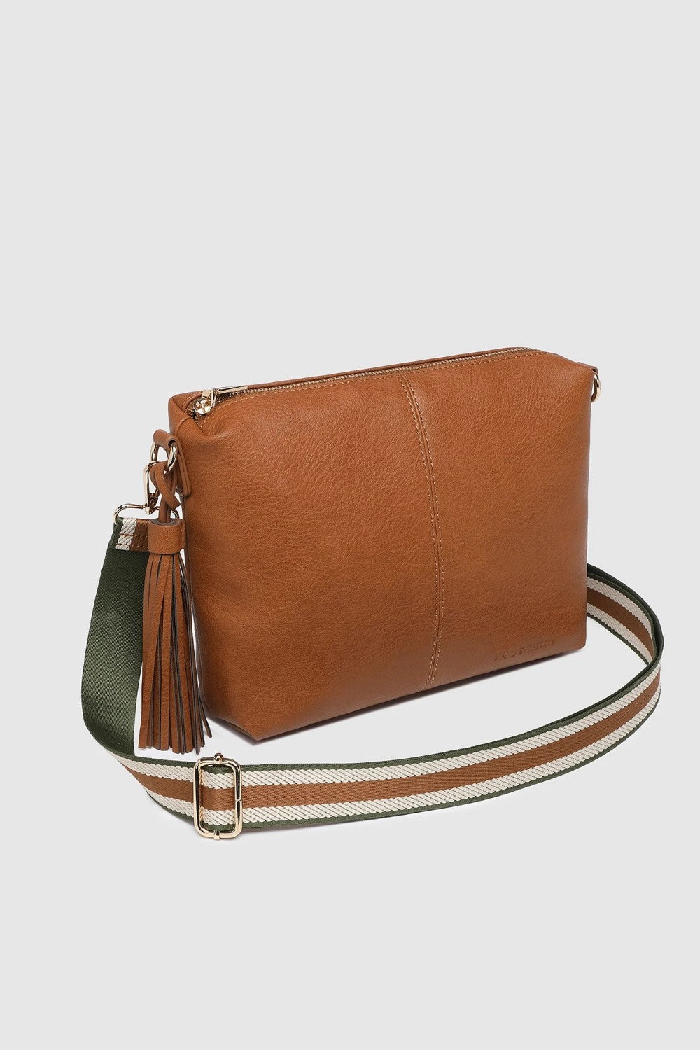A brown leather crossbody bag with a tassel detail and a wide, striped adjustable shoulder strap, shown against a light gray background.