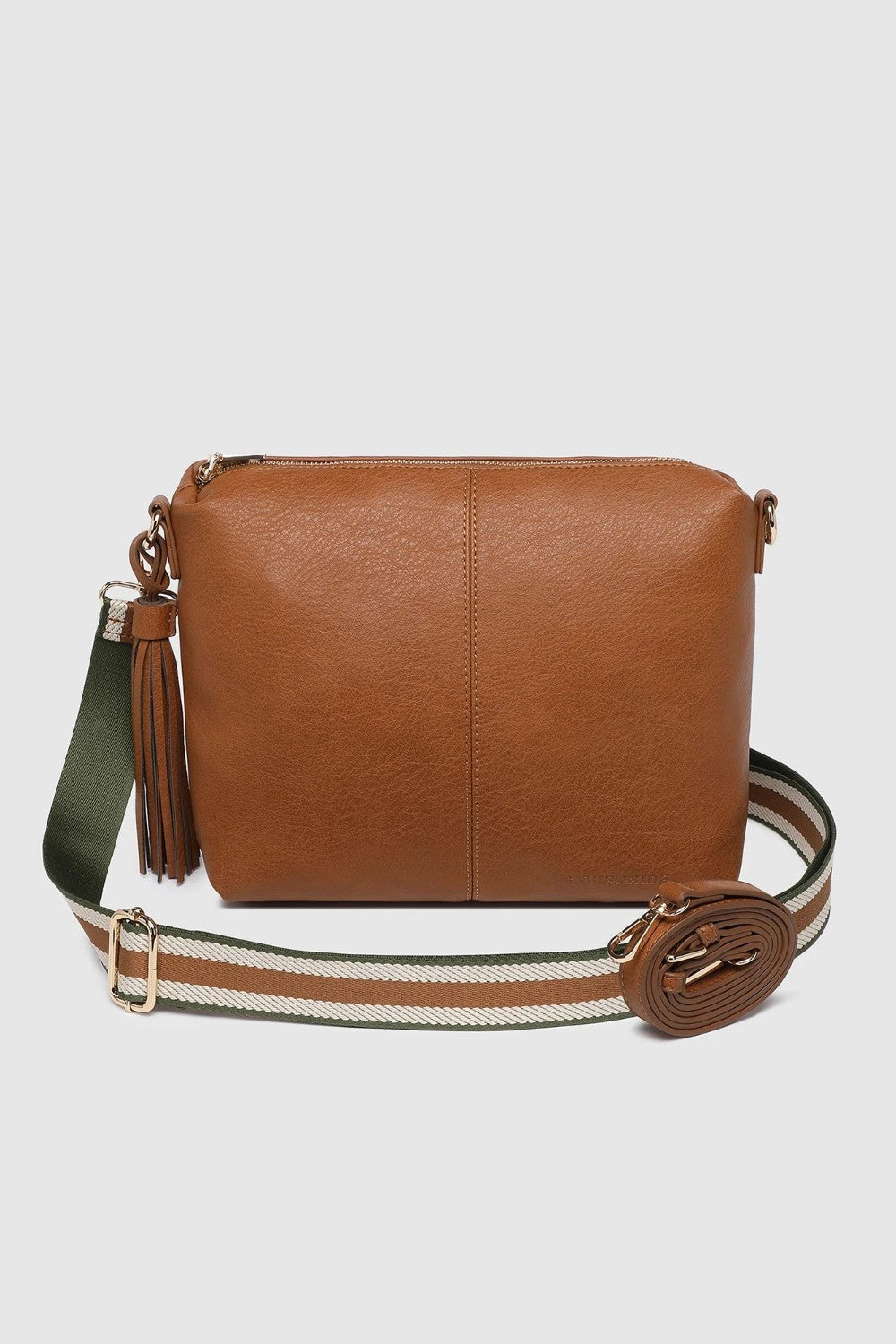 A brown leather crossbody bag with a wide woven strap featuring green, white, and brown stripes, and a tassel detail on the side, shown against a light gray background.