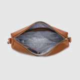 A tan leather bag shown from a top-down view, open to reveal a striped black and white interior lining with gold-tone zipper hardware.