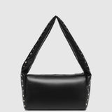A black leather shoulder bag with a wide, strap-like top handle and silver-tone studs along the edges, shown against a light gray background.