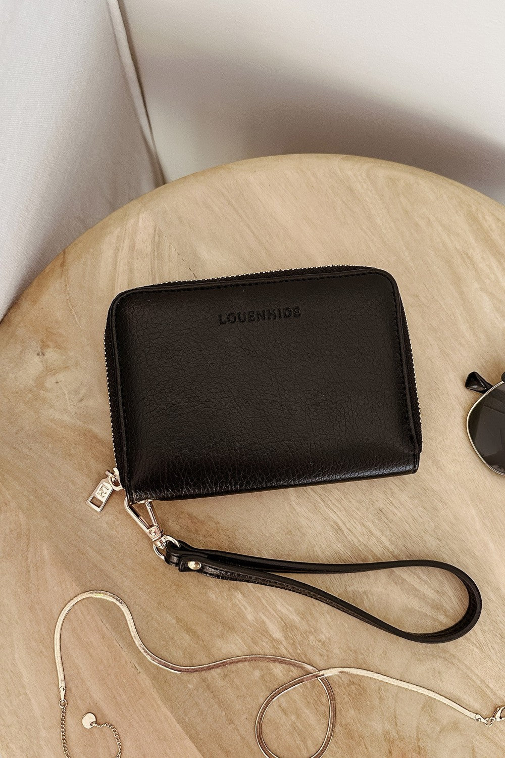 Black wallet with a strap on a wooden surface, featuring the brand 'Louenhide'.