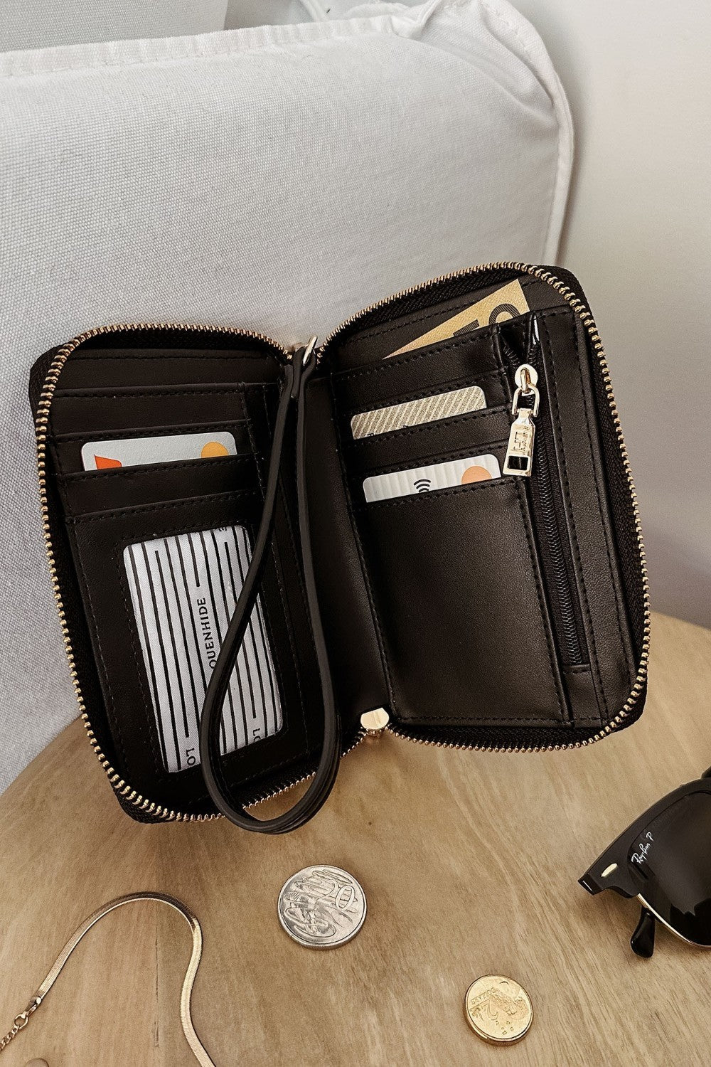 Black wallet with a strap on a wooden surface.