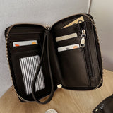 Black wallet with a strap on a wooden surface.