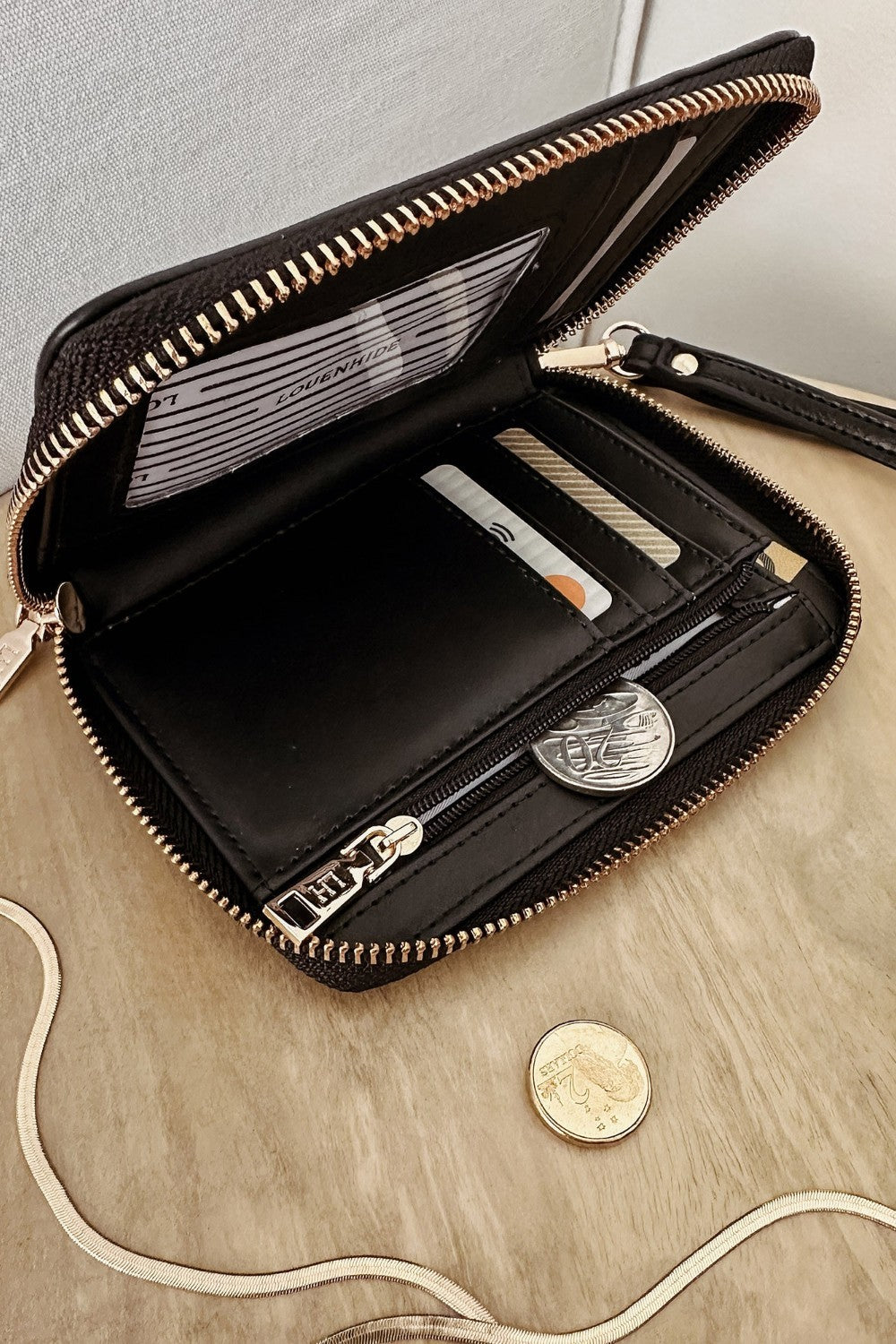 Black wallet with a strap on a wooden surface.