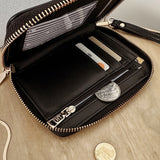 Black wallet with a strap on a wooden surface.