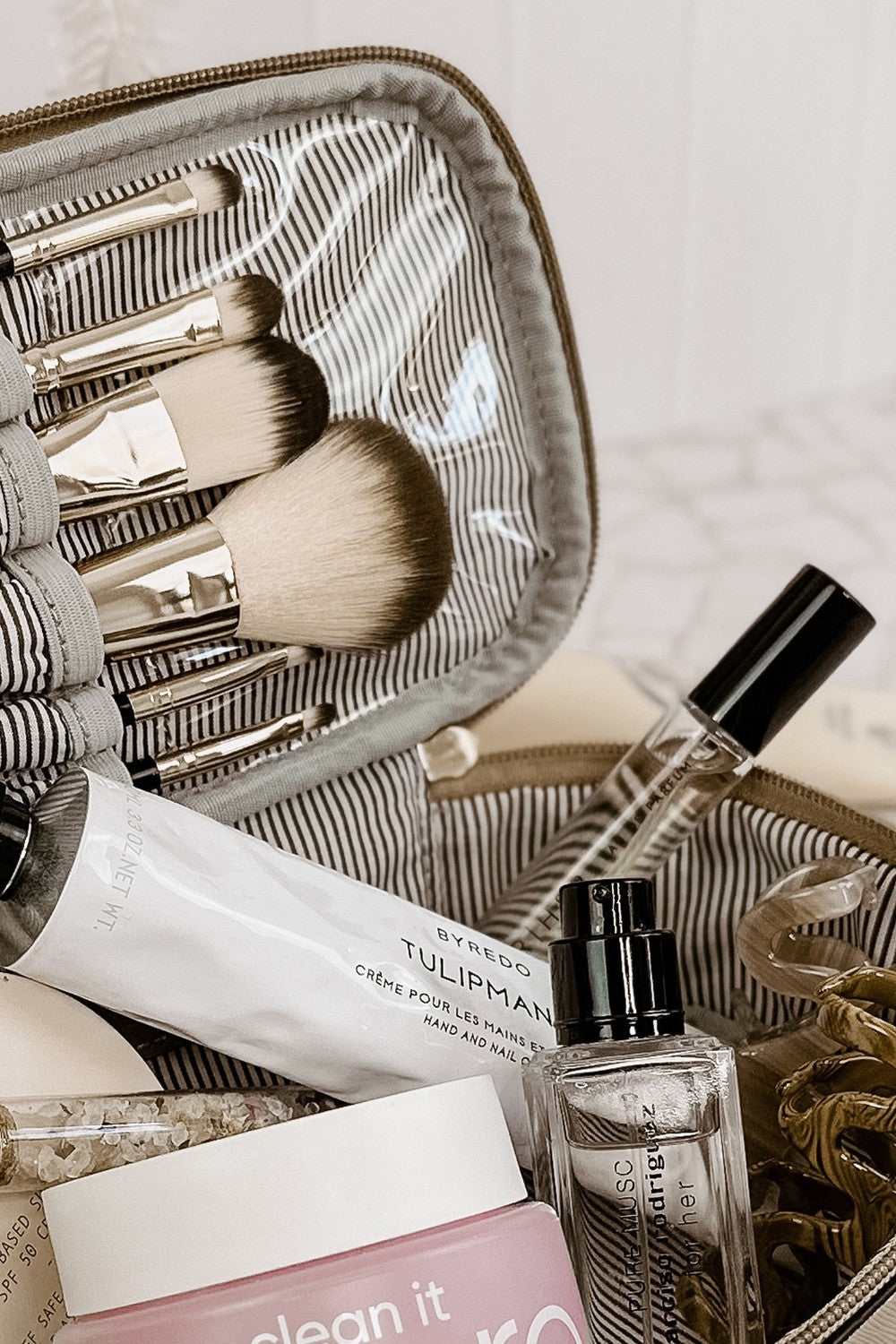 Makeup brushes, skincare products, and a perfume bottle in an open makeup bag.