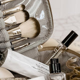 Makeup brushes, skincare products, and a perfume bottle in an open makeup bag.