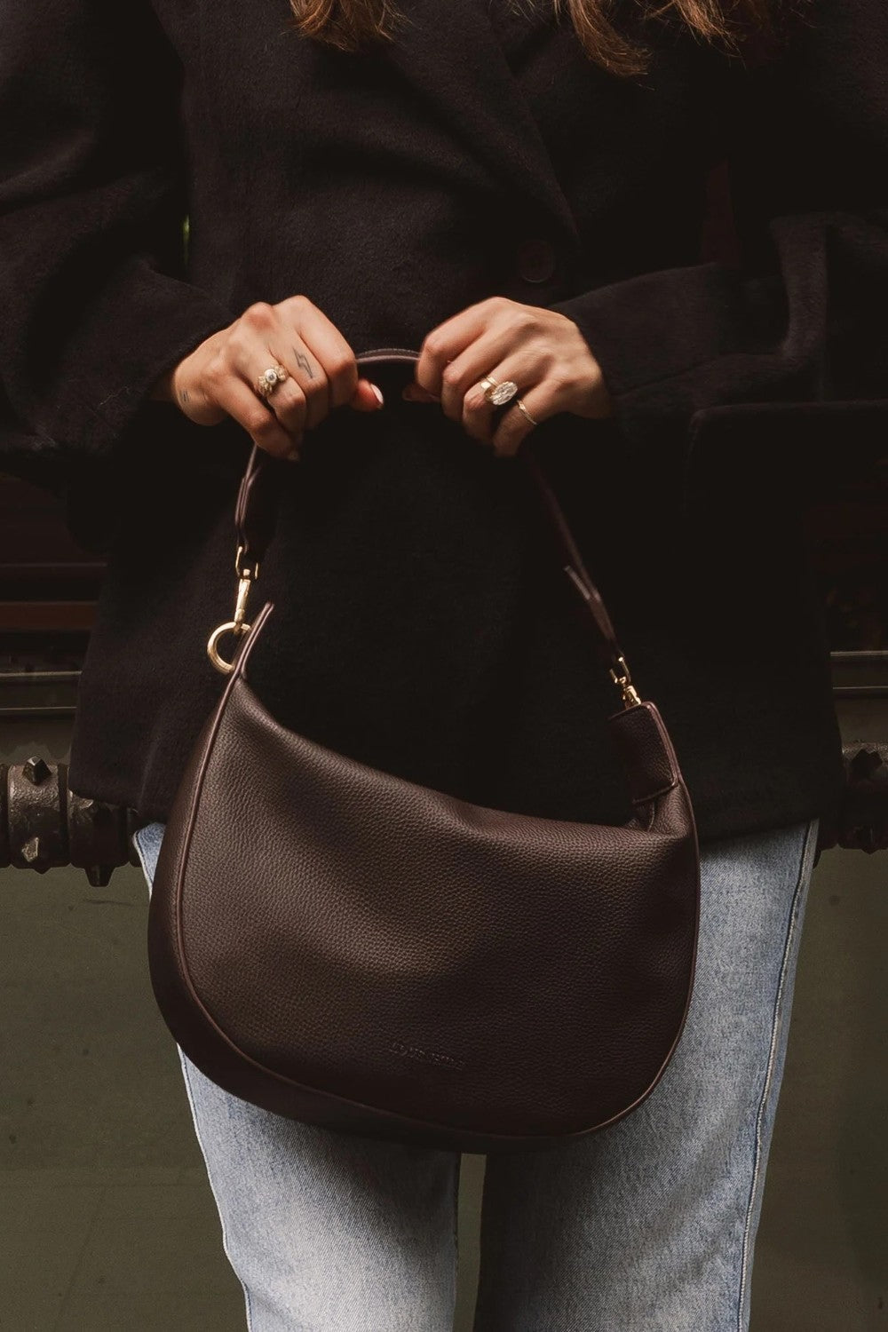 Person holding a brown leather handbag with a blurred background
