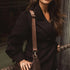 Woman holding a brown leather bag against a dark background