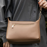 Person holding a brown pleather handbag with a blurred background