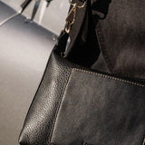 Black pleather handbag with 'LOUENHIDE' branding on a blurred background