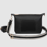 Black pleather crossbody bag with a strap on a light gray background