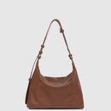 Brown leather handbag with a strap on a light gray background