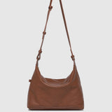 Brown leather handbag with a strap on a white background