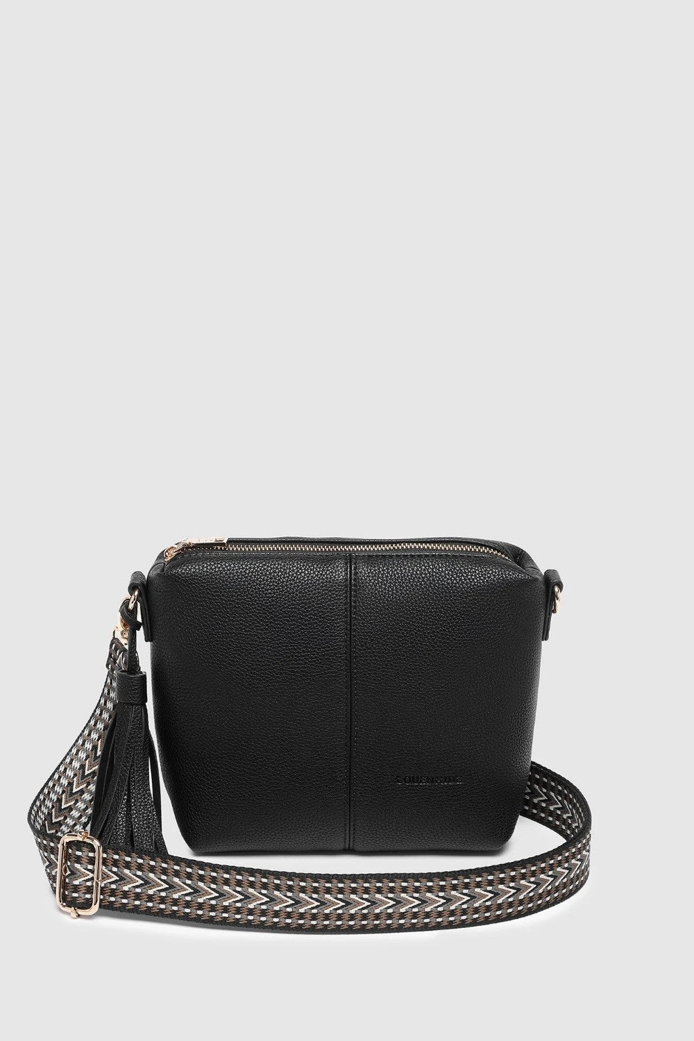 A black pebbled leather crossbody bag with a zip-top closure, a tassel detail, and a wide woven strap with silver-tone hardware, shown against a light gray background.