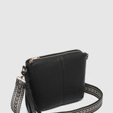 A black pebbled leather crossbody bag with a woven black and silver patterned shoulder strap and silver-tone hardware, shown on a light gray background.