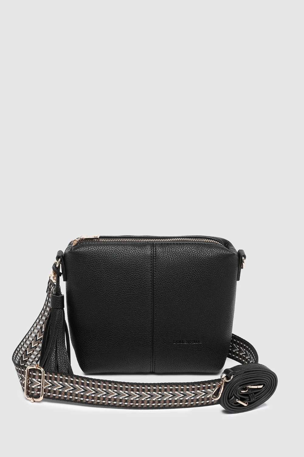 A black pebbled leather crossbody bag with a zippered top and a wide woven strap plus an additional black pleather strap, shown against a light gray background.