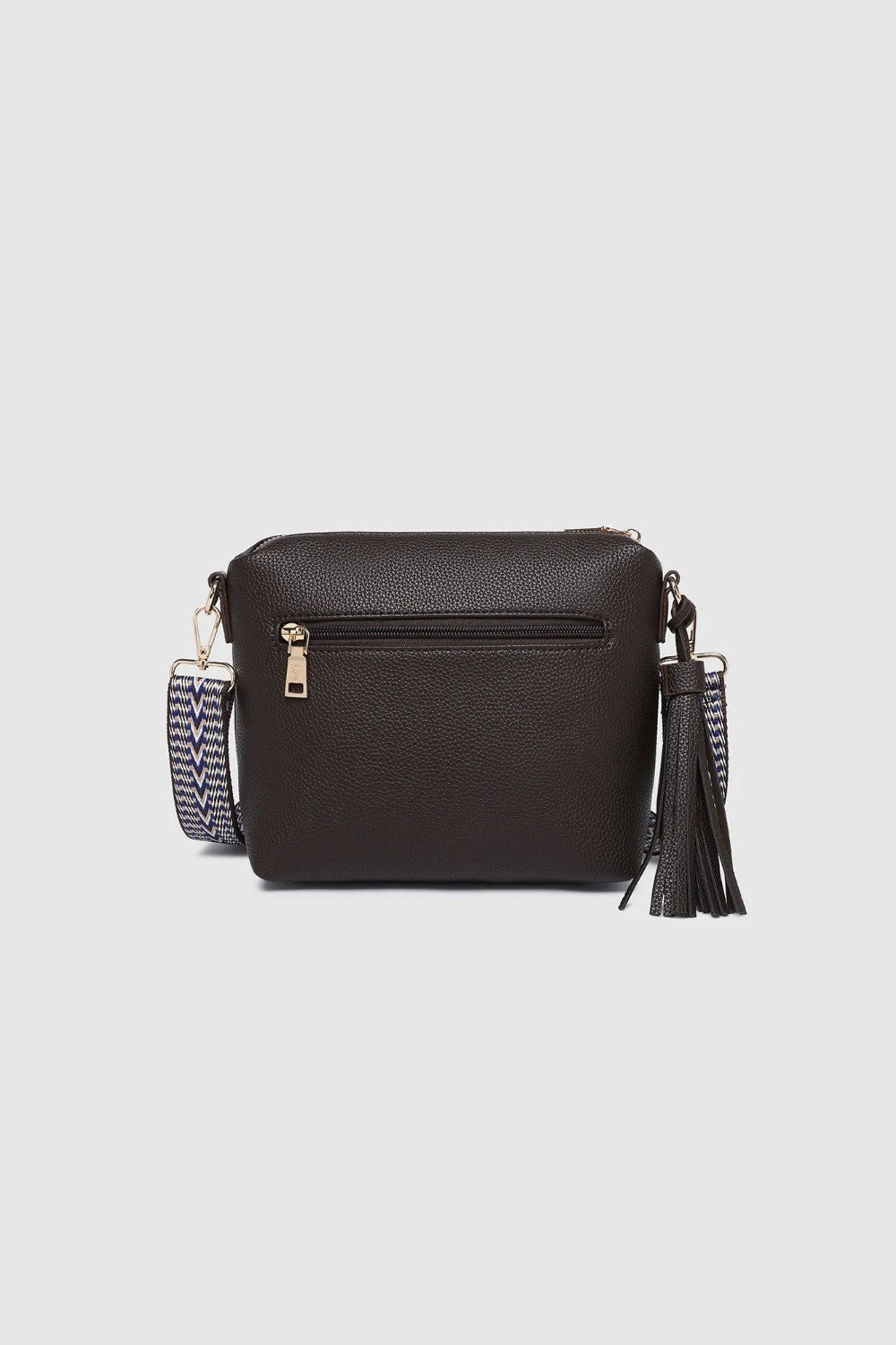 A dark brown textured faux-leather crossbody bag with a patterned strap and a tassel accent, shown against a light gray background.