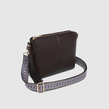 A dark brown leather crossbody bag with a patterned woven strap featuring a gold-tone buckle, shown on a light gray background.