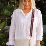 Woman wearing a white shirt with a beige crossbody bag outdoors
