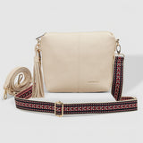 Beige handbag with a strap featuring red and black patterns on a light gray background