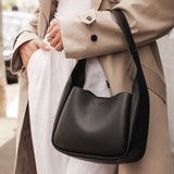 Person wearing a beige coat holding a black handbag.