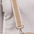 Beige crossbody bag with textured strap on a light gray background