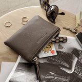 Brown pleather wallet with sunglasses, keys, and cards on a magazine
