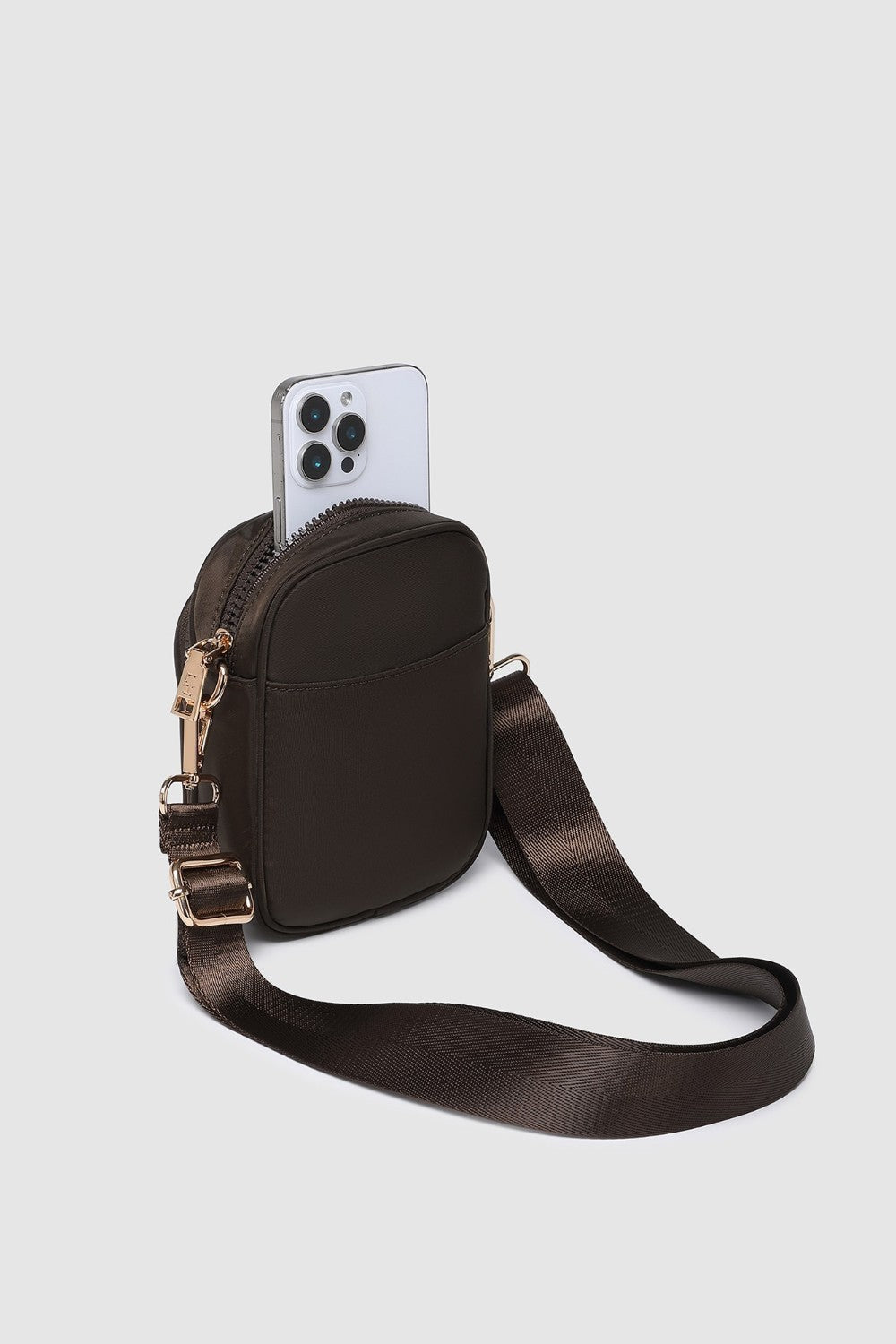 Brown crossbody bag with a phone case on a light gray background